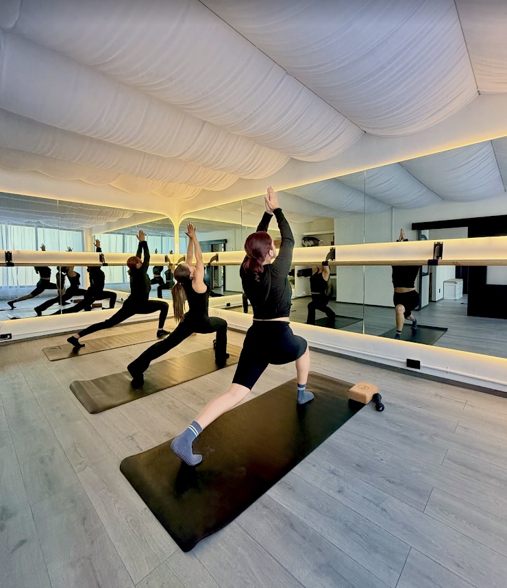 Clase grupal de yoga frente a los espejos de Aera Studio