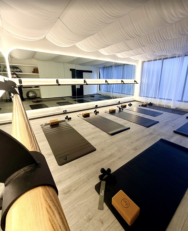 Salón de Aera Studio con tapetes preparados, espejos y techo de tela blanca