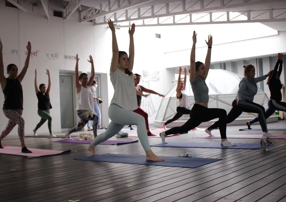 Clase grupal de yoga en el salón luminoso de AgoraLucis