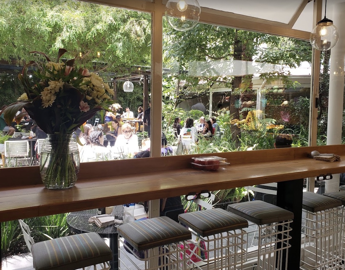 Área con barra, asientos y vista a un jardín en AgoraLucis