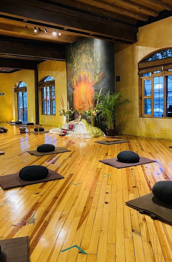 Sala de meditación del Centro Budista de la Ciudad con piso de madera y cojines