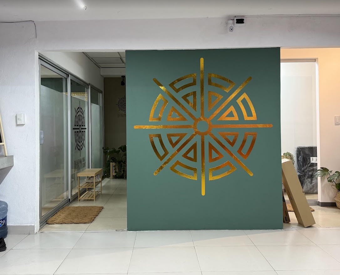 Entrada de Dharma Yoga Studio con emblema dorado sobre pared verde