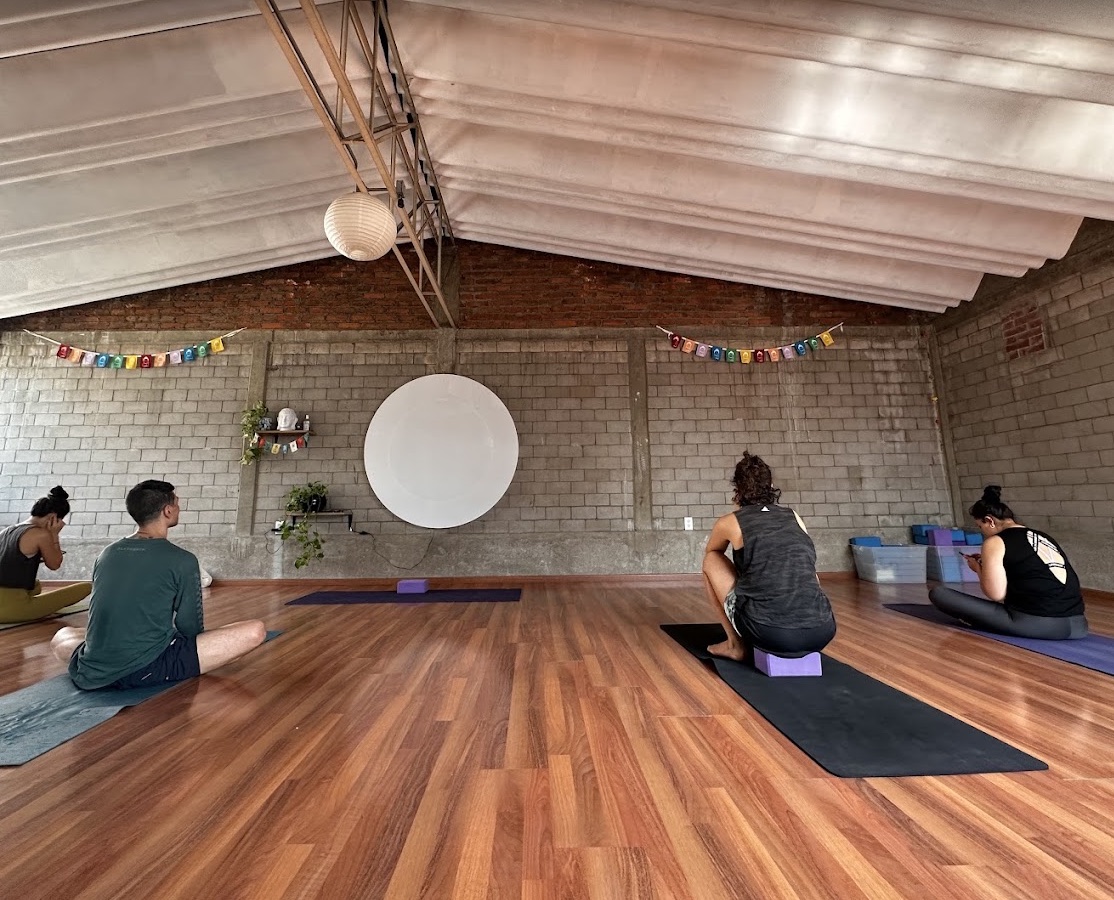Interior de Power Flow Yoga con piso de madera y personas preparándose para una clase