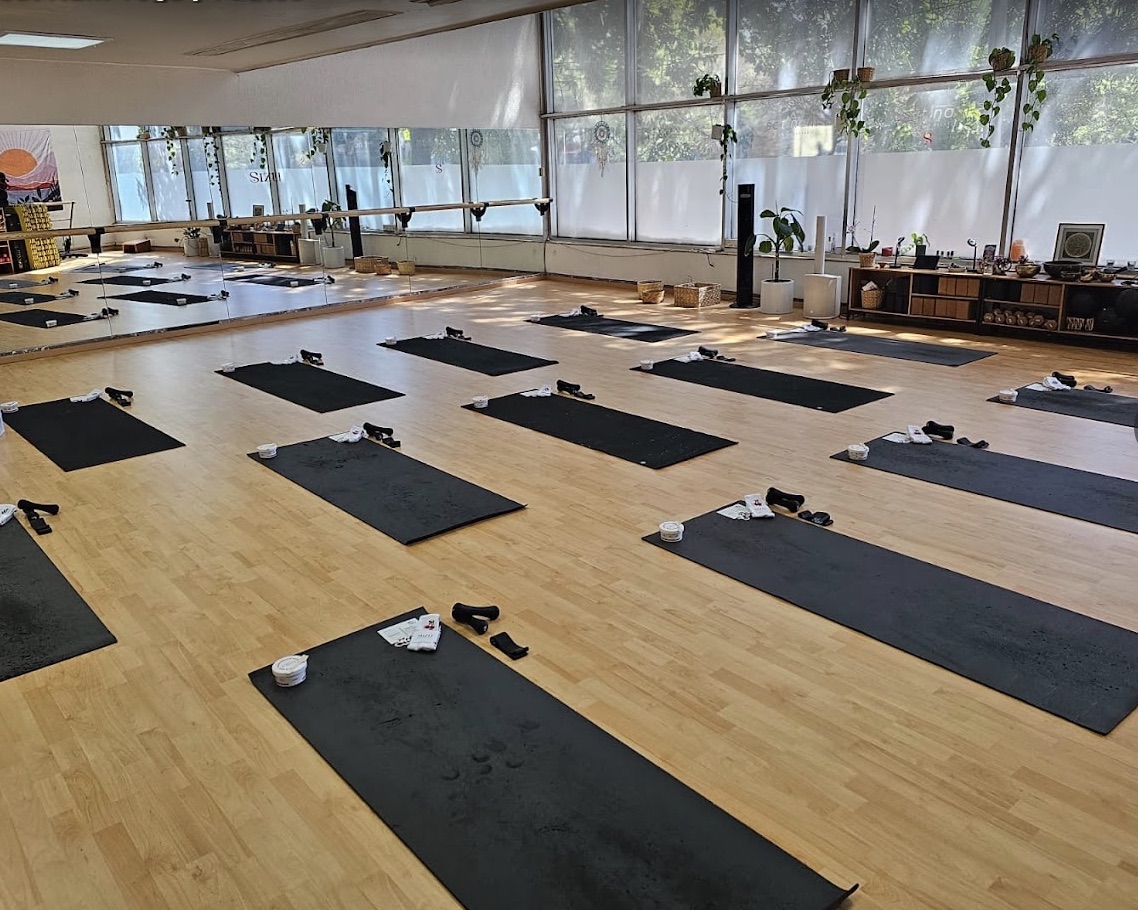 Salón de Sat Nam Yoga y Pilates preparado con tapetes junto a ventanales y espejos